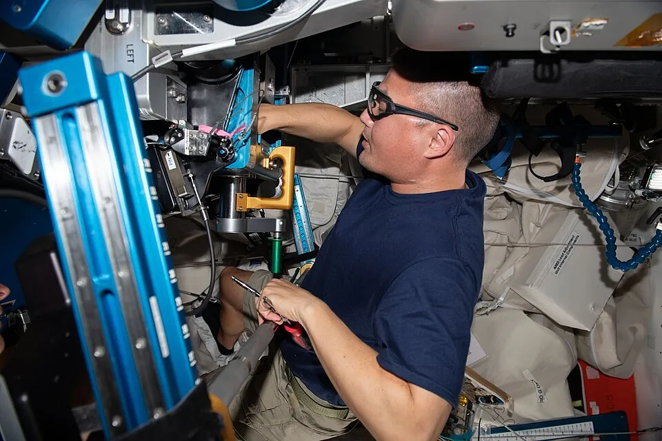 国際宇宙ステーションで運動用の装置を整備する宇宙飛行士
